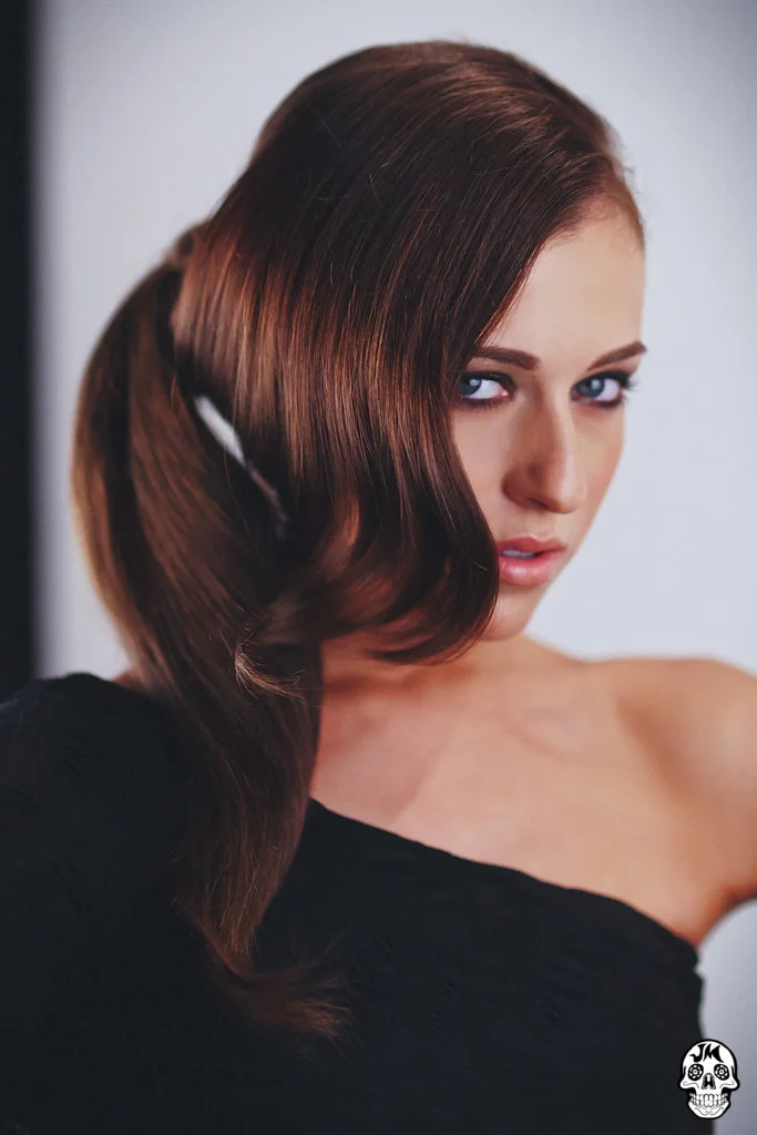 Model wearing one shoulder black top and a side ponytail styled by Dennis Clennenden of VCI artists